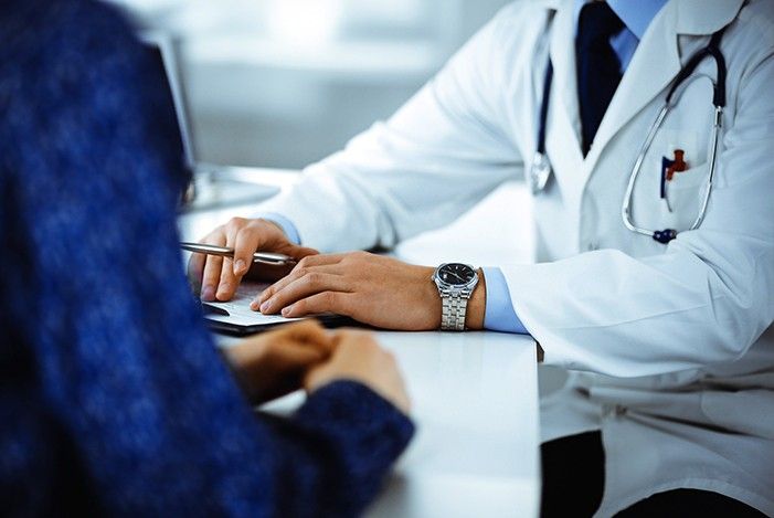 Arzt und Patient sitzen sich gegenüber Arzt hält Kugelschreiber in der Hand.jpg