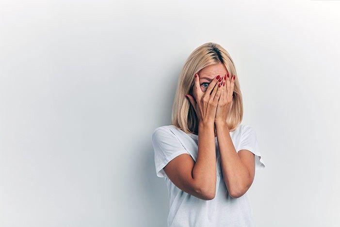 Frau hat hände vor dem Gesicht und und blickt mit einem auge durch die Hände.jpg