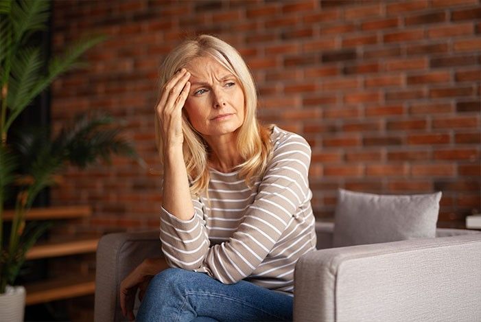 Frau nachdenklich sitzend in einem polsterstuhl.jpg