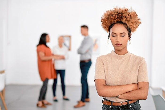 Frau steht alleine hinter ihr sprechen Personen zusammen sie ist alleine.jpg