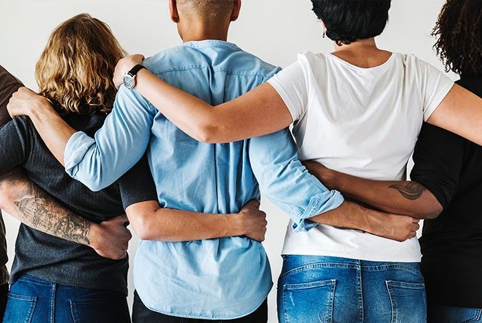 Menschen von hinten in einer Reihe vor einer wand die sich am Rücken umarmen.jpg