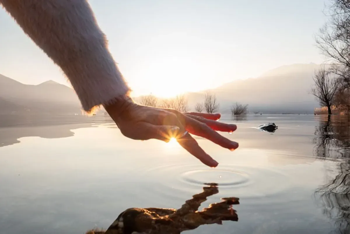 hand-beruehrt-wasser-im-sonnenuntergang